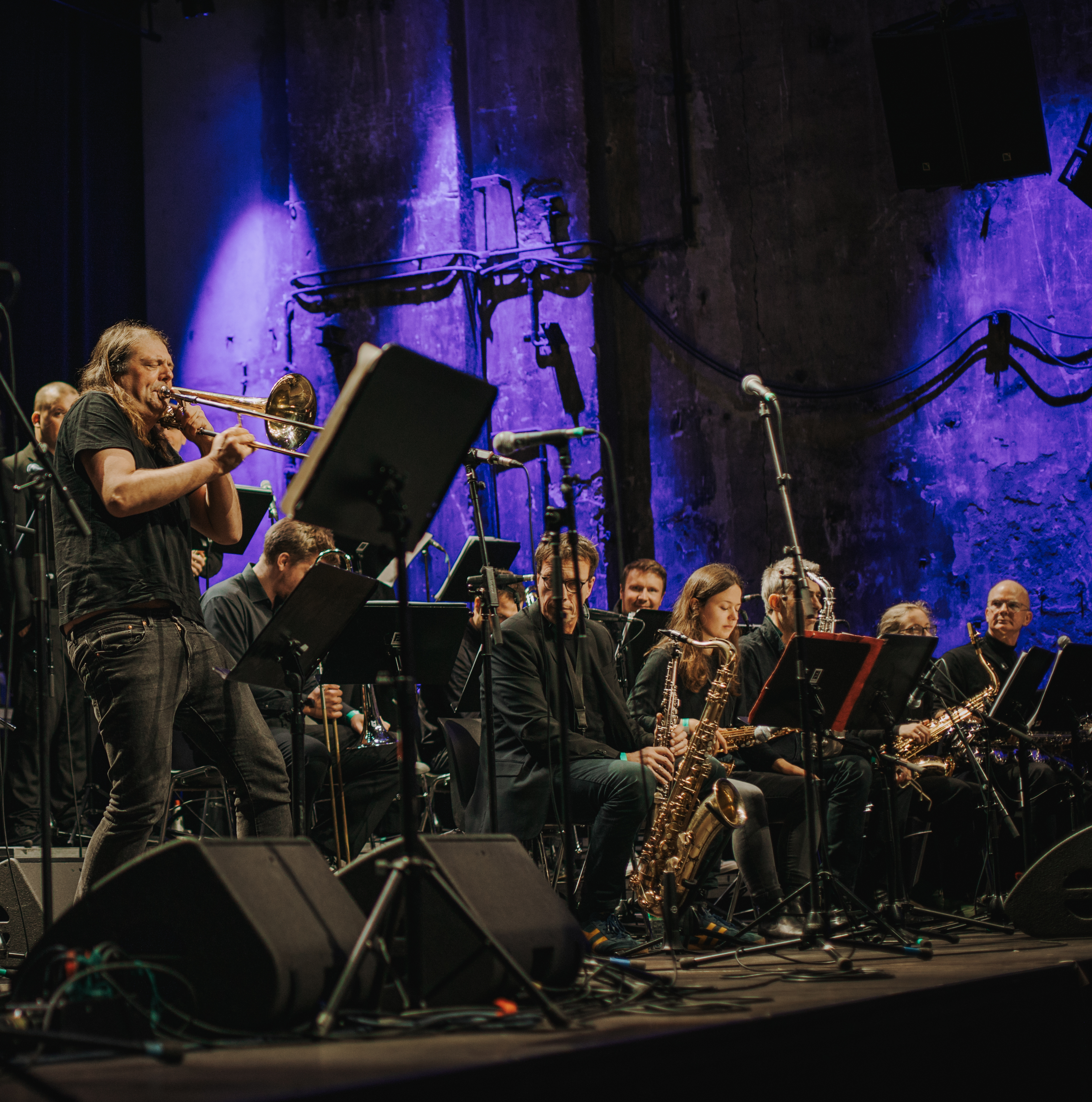 Posaunist beim Solieren mit Bigband im Hintergrund Posaunist beim Solieren mit Bigband im Hintergrund